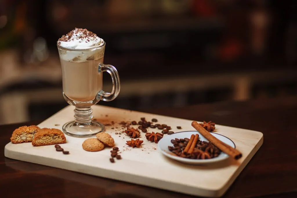 mocha cofee drink with cinnamon, star anise, coffee beans, and cookies in a wooden board