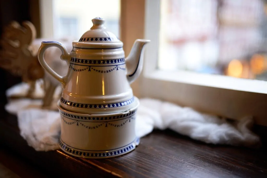 a ceramic coffee pot near a window