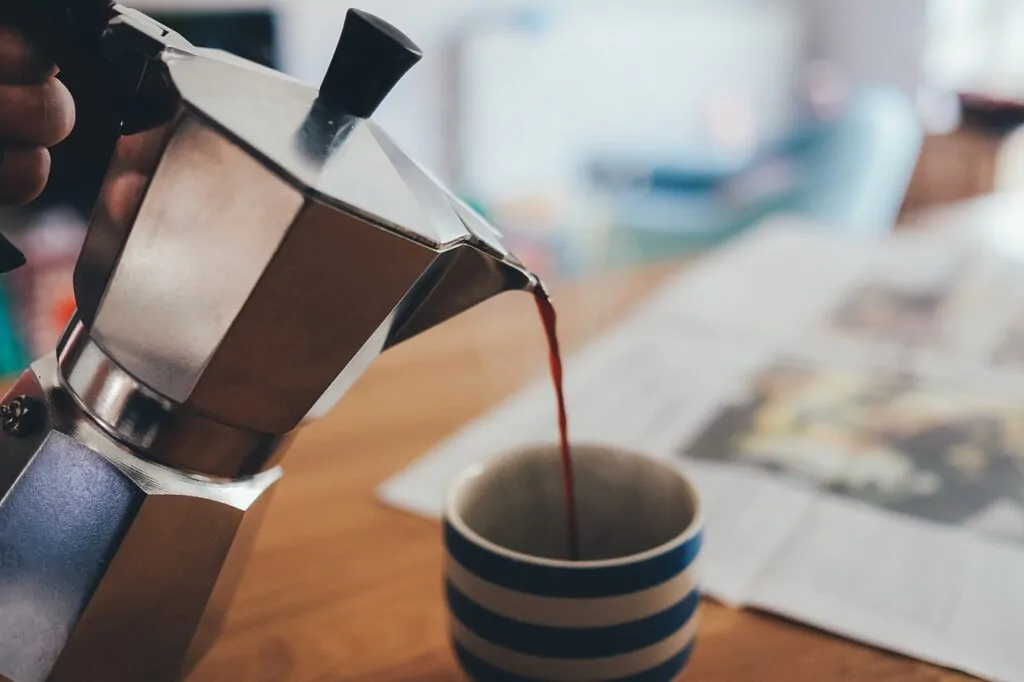 Moka pot pouring a coffee in a cup