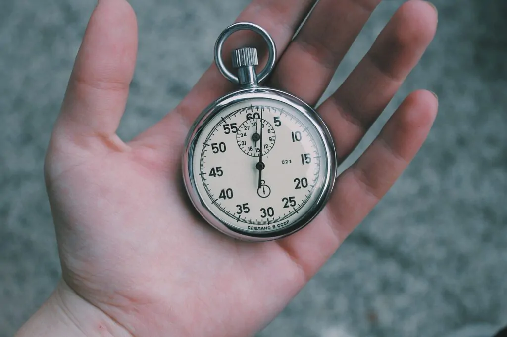 A silver mechanical watch placed in a palm of a hand