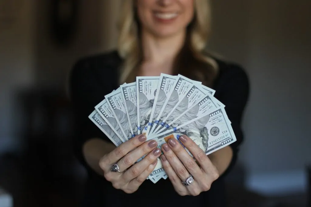 woman in business attire holding dollar bills