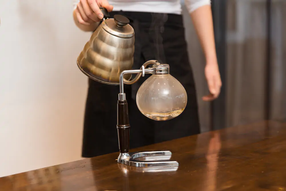 a man pouring coffee using siphon coffee maker