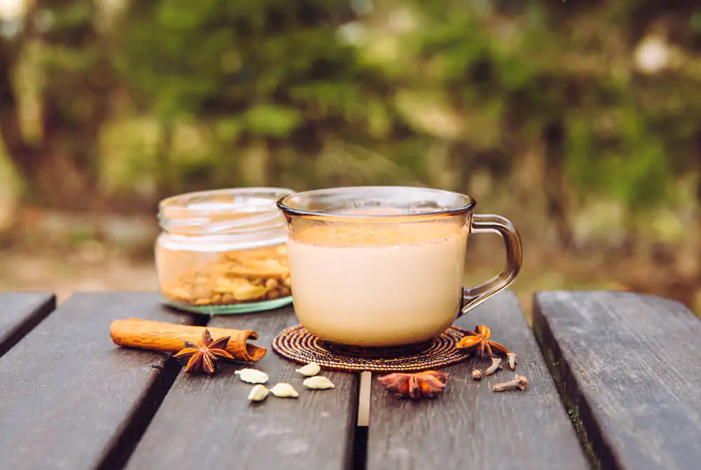 a cup of chai latte and some spices on a wooden table pic for does chai latte have caffeine
