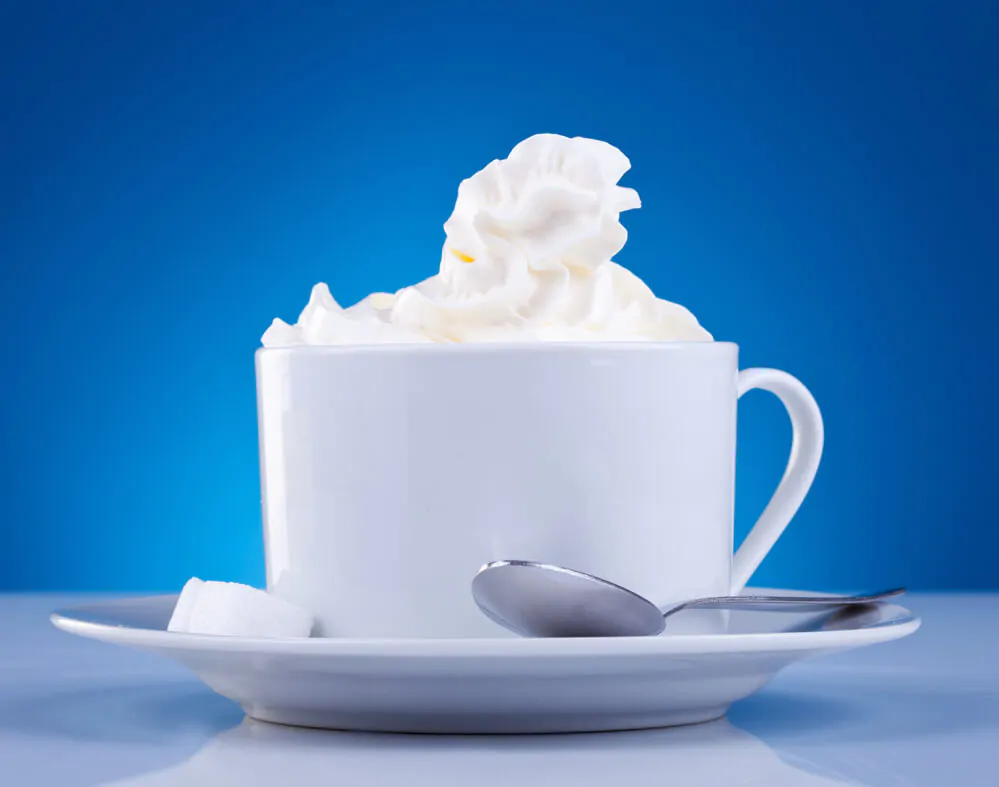 Freeze coffee creamer; A cup of coffee with creamer in a blue background.
