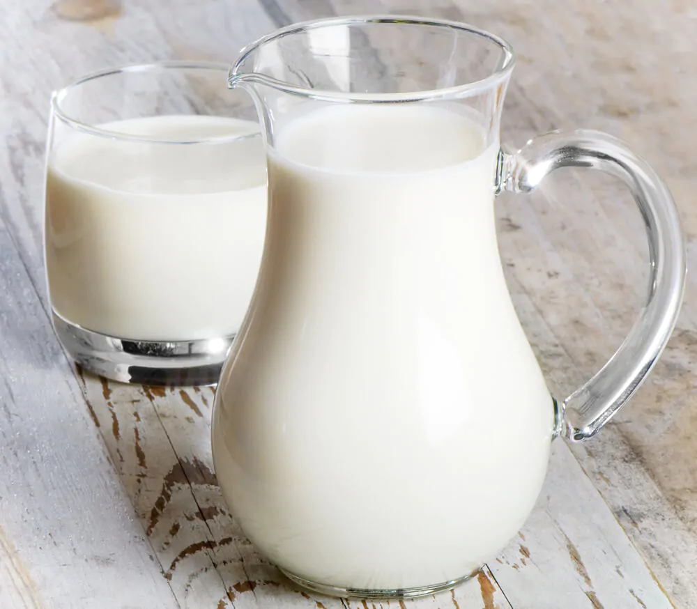A pitcher of milk and a glass of milk