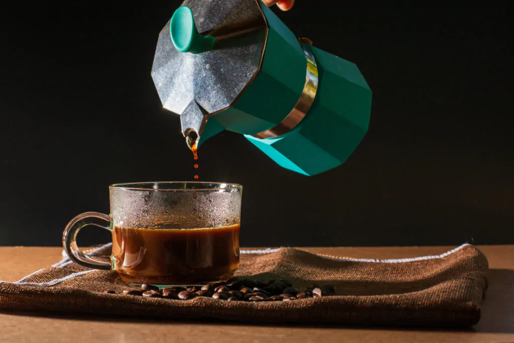 Pouring coffee from a green Moka pot