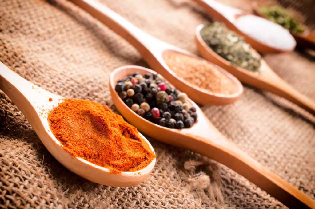 What spices are in a chai latte. Different kinds of spices in a wooden spoon with the heads of the spoon placed side by side each other.
