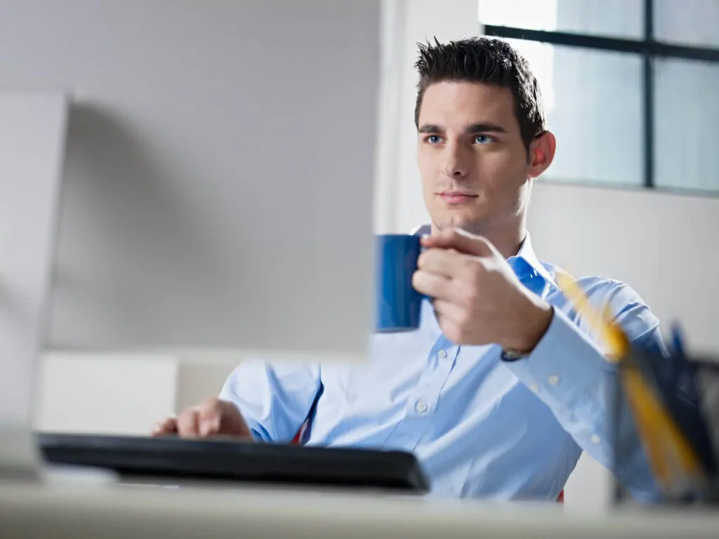 a caucasian man drinking coffee while focusing on his job