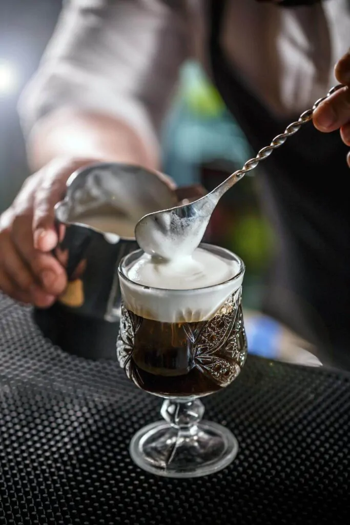a cup of Irish coffee being mixed with milk froth