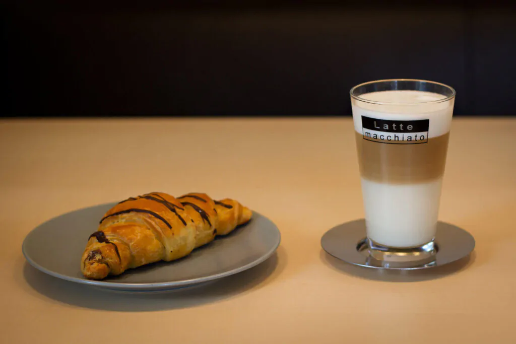 a cup of macchiato latte with a bread