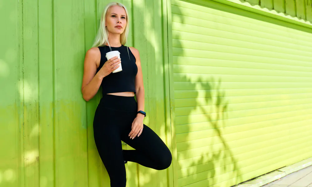 Caucasian woman drinking cup of coffee before running