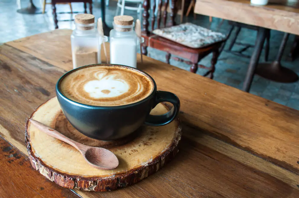 a cup of hot latte on a wooden table