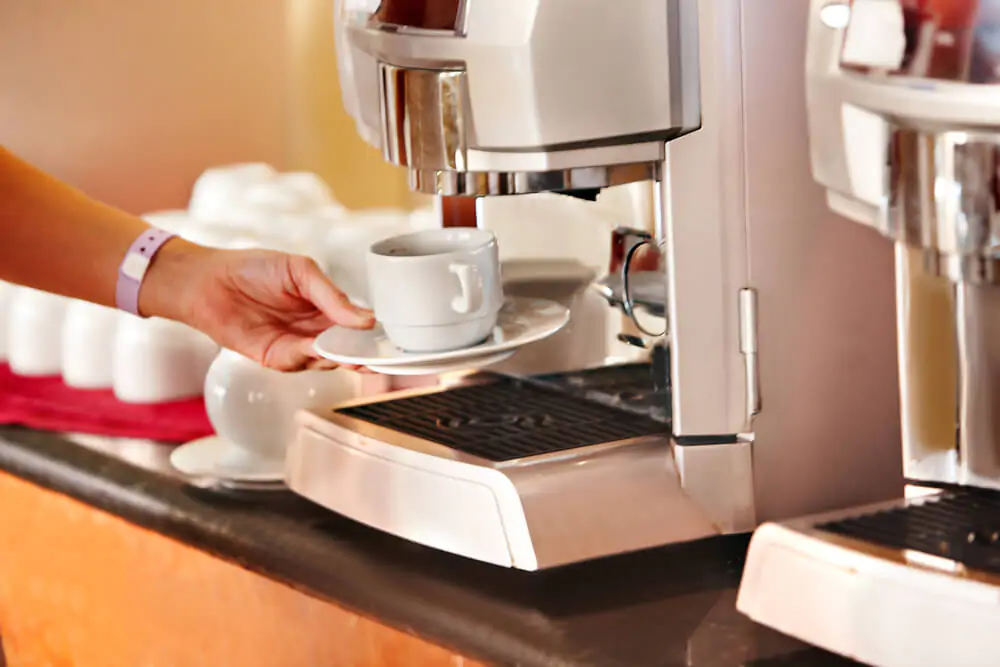 a woman using Keurig machine on her cup of coffee