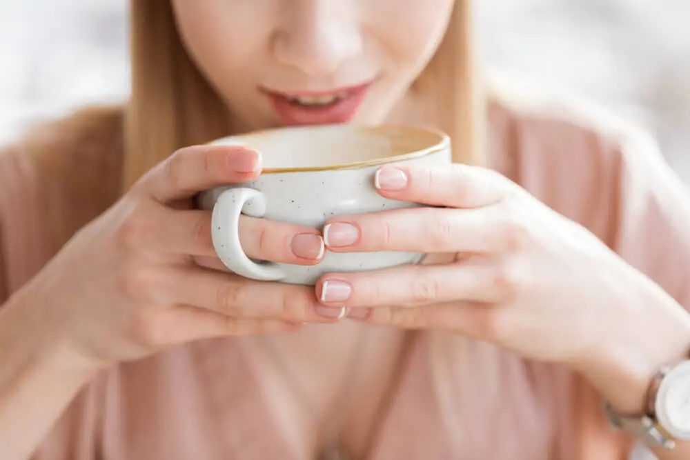 a woman holding her cup of coffee using both hands
