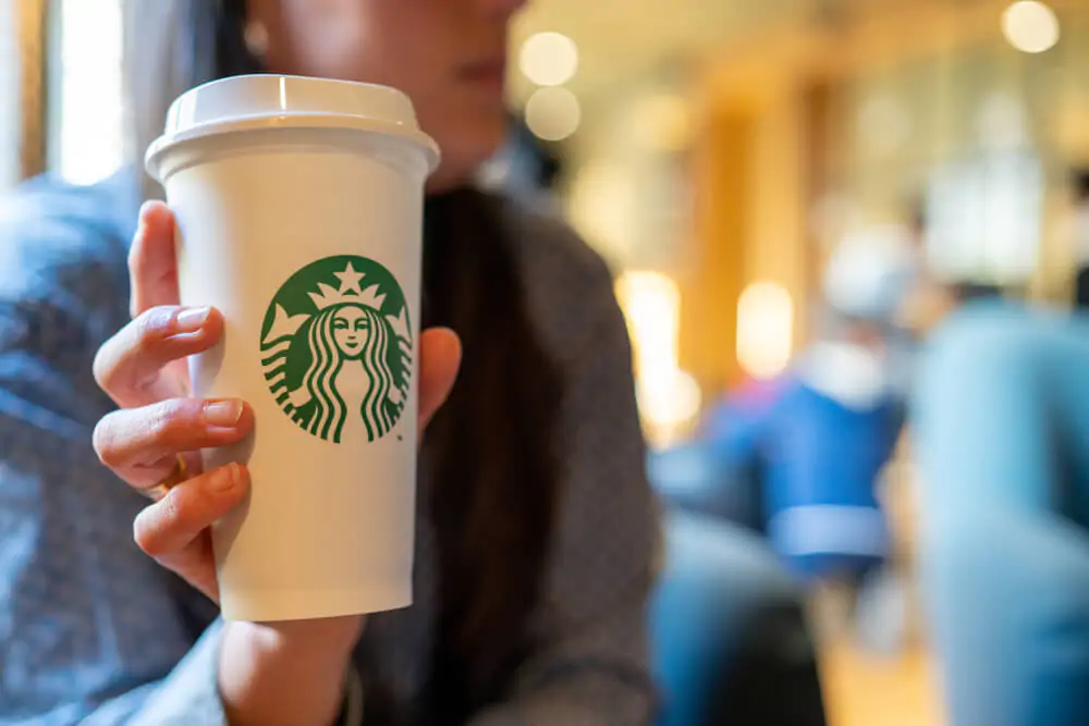 a woman holding a Starbucks drink 