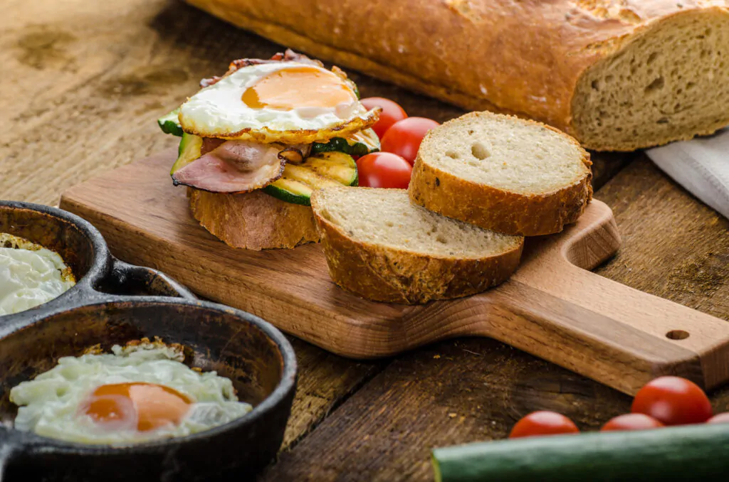 Rustic breakfast, fresh eggs baked in griddles, bacon, vegetables, fresh orange and rustic bread