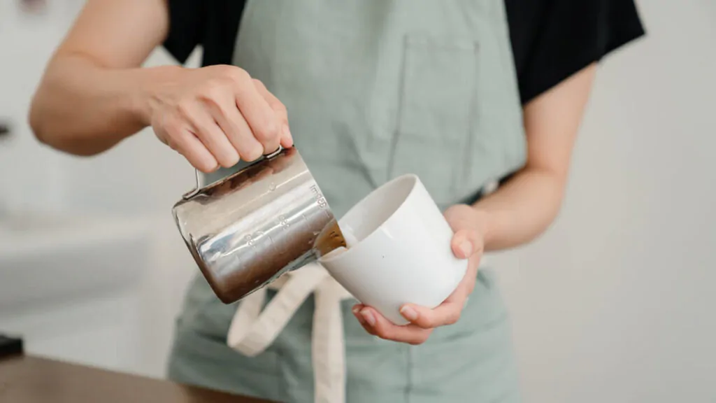 barista pouring creamer to a cup