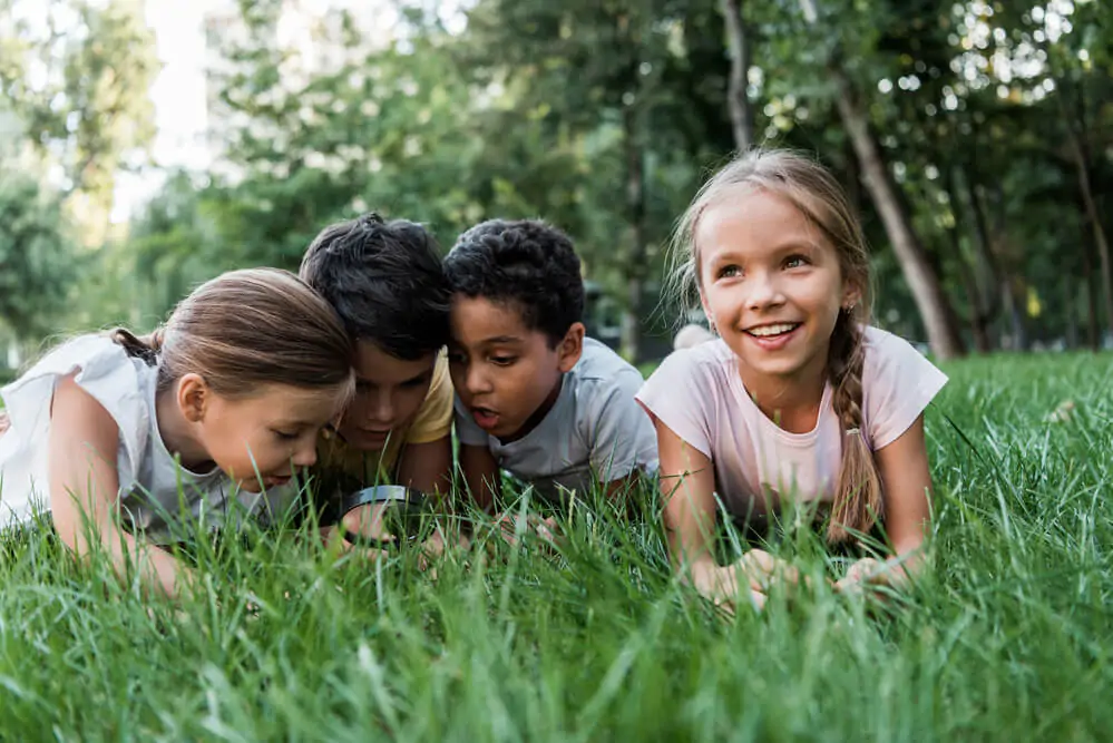 cute multicultural children looking at green grass