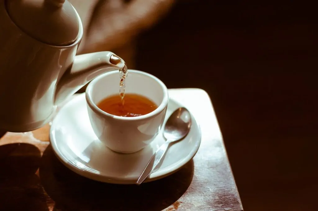 a hot tea being poured down on a cup with a spoon