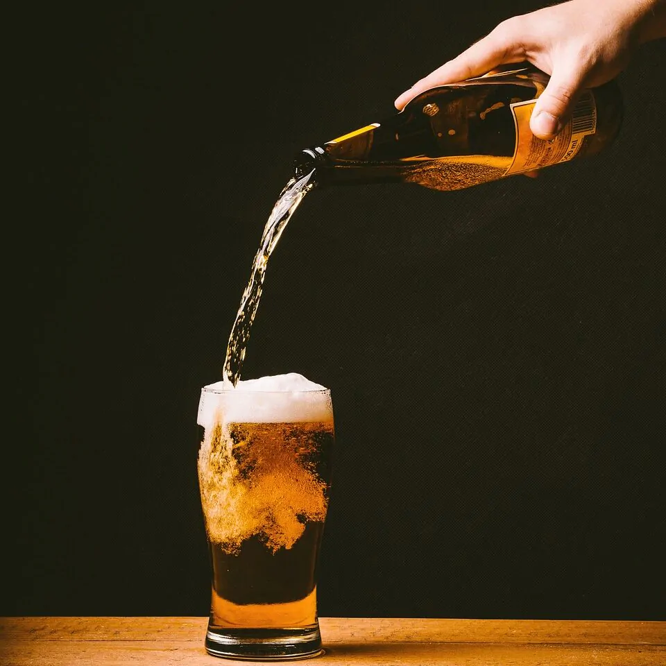 unidentified person pouring beer on a pint glass