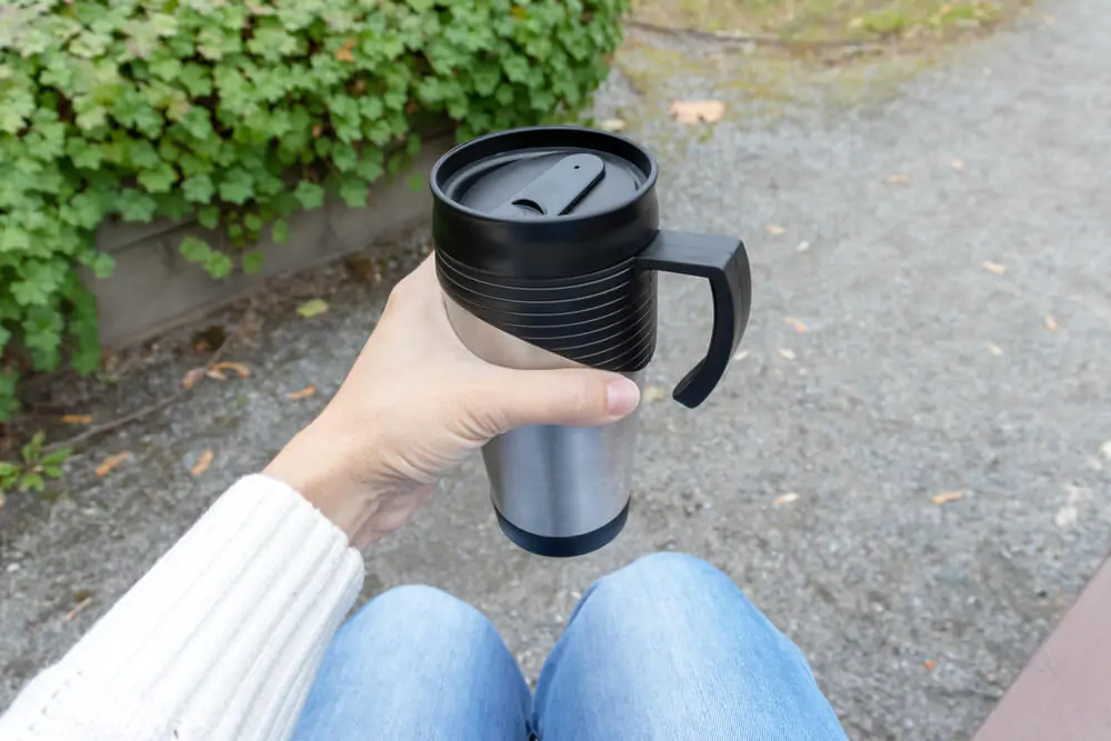 a woman sitting while holding her travel mug