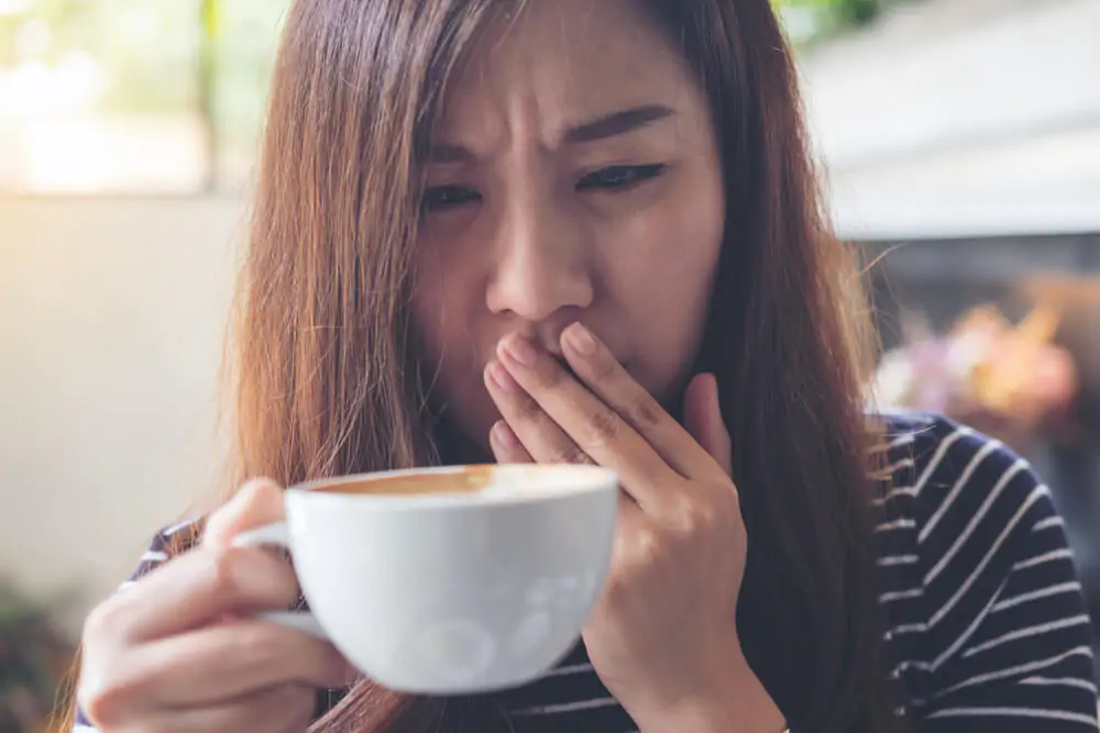 Asian woman holding hot coffee feeling strange after tasting