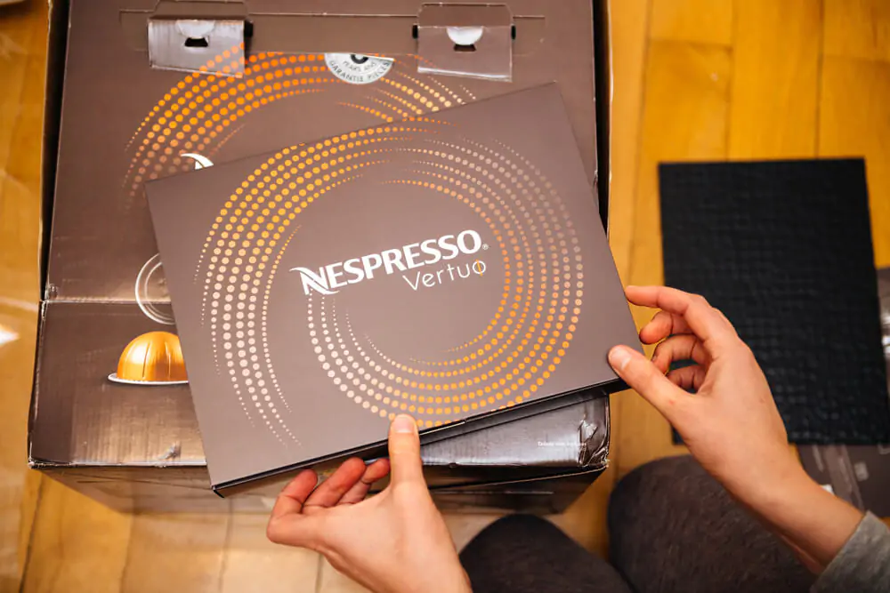 woman holding unboxing new package of with multiple colorful Nespresso Vertuo coffee capsules