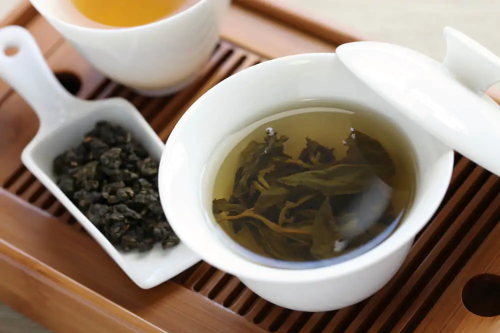 Oolong tea prepared in a ceramic cup placed in a wooden tray