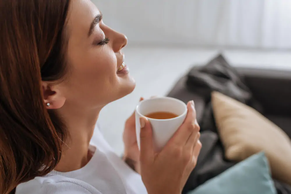 woman smiling while holding her tea