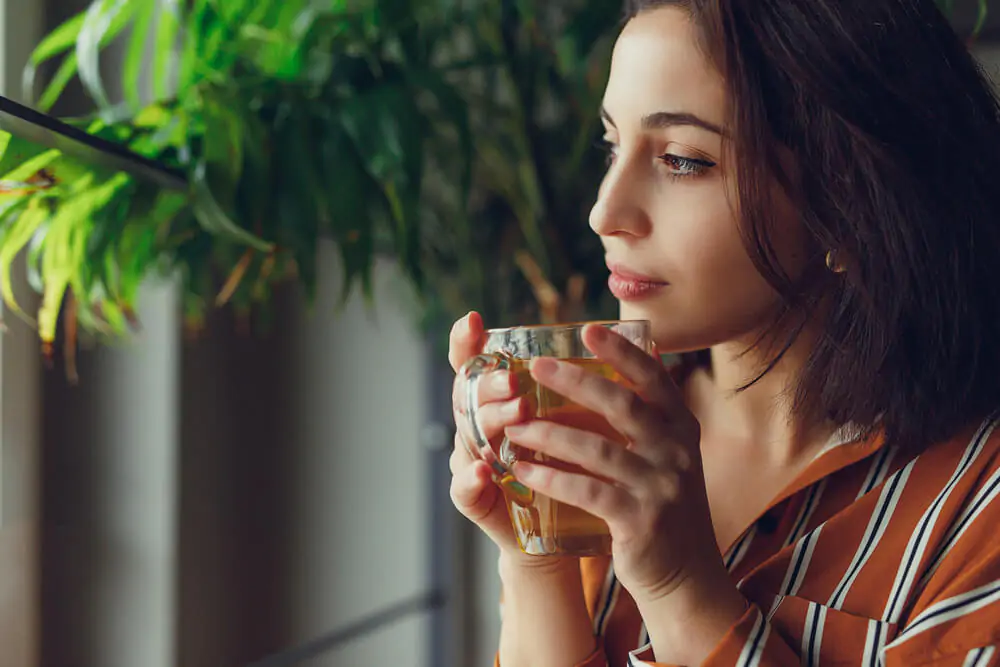 a close-up shot of a woman looking from a distance while holding a tea