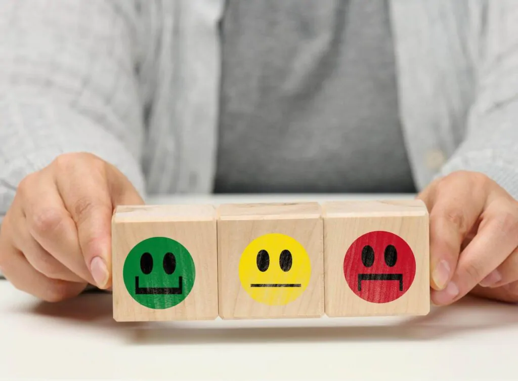 wooden blocks with different emotions from smile to sadness and a woman's hand