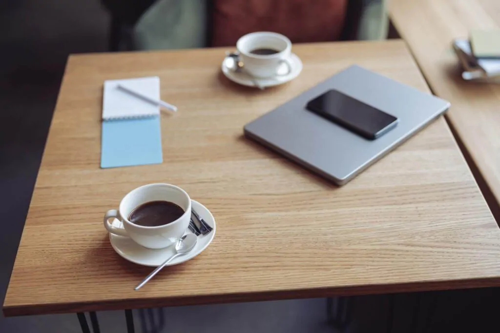 Wooden table with cups of coffee, a laptop and a phone - why a wooden coffee table