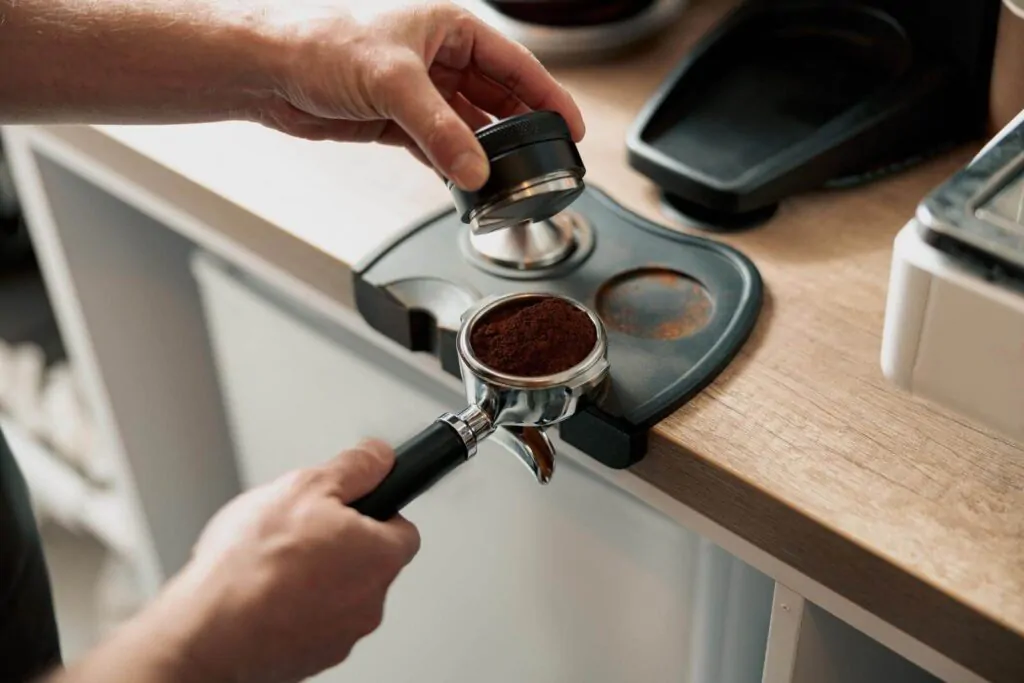barista hands holding tamper and pressing ground coffee - Why tamp coffee