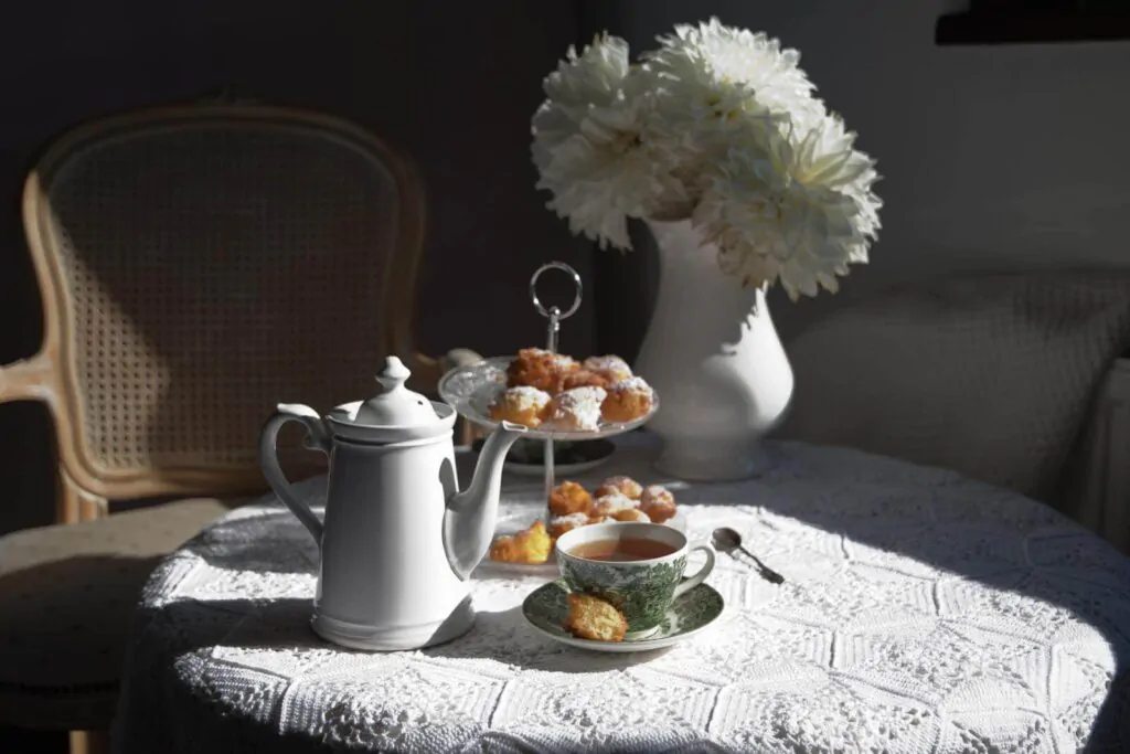 a tea party with kettle, flower vase, a tea, and cupcakes