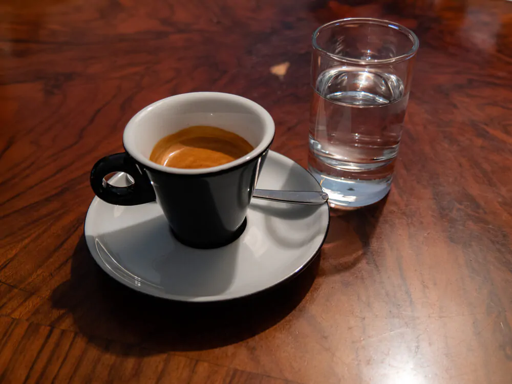 A cup of espresso served with sparkling water