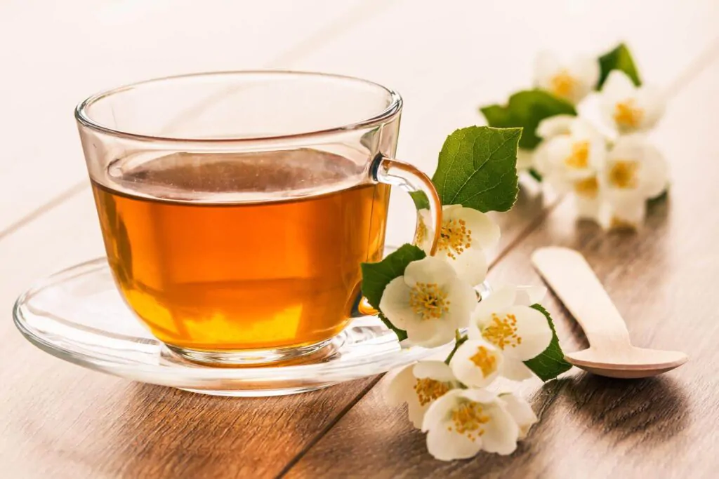 Glass cup of green tea with white jasmine flowers - Is Jasmine tea caffeinated