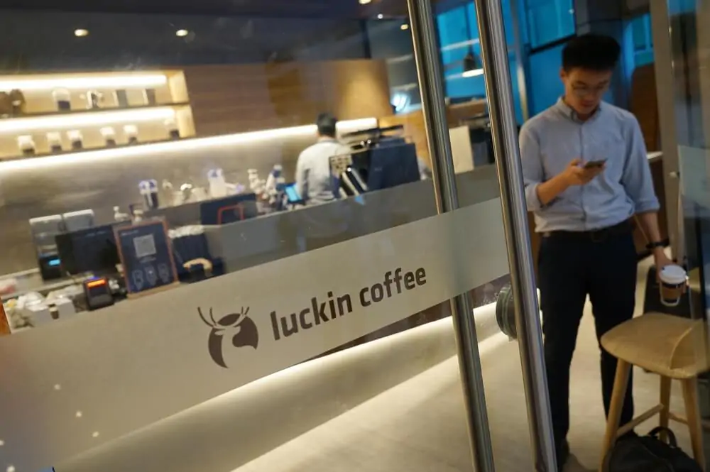 A young customer walks out of a store of China's new coffee brand Luckin coffee