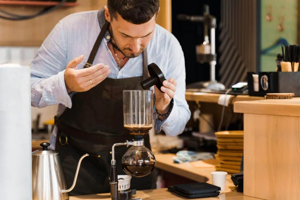 Barista sniffs flavored coffee in syphon device