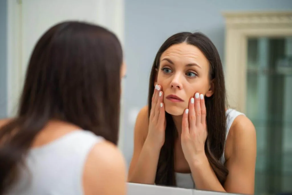 woman checking her eyebags in a mirror