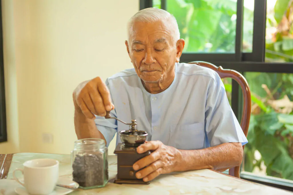 Asian senior man with vintage coffee grinder 