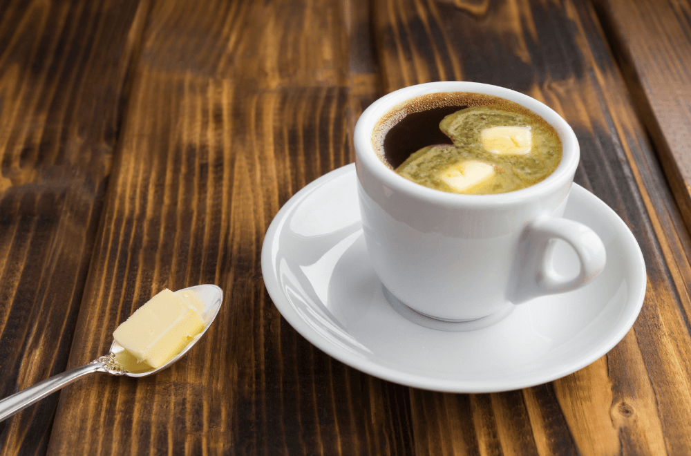 A cup of coffee with butter on a wooden table