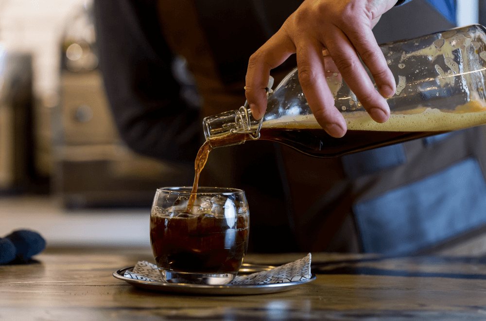 Barista pours coffee into a glass full of ice