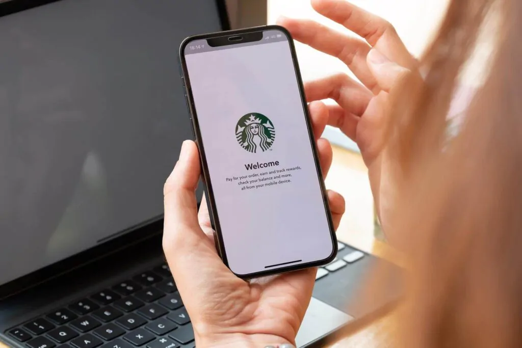 A woman holds iPhone 12 showing Starbucks logo on screen