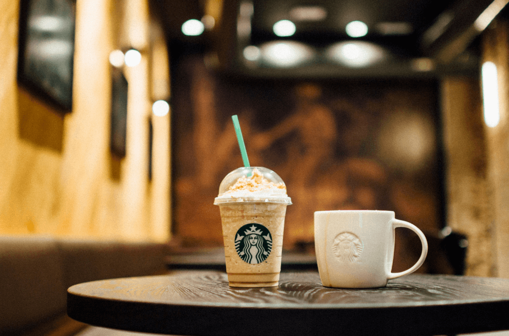 Starbucks frappucino and a mug on a wooden table