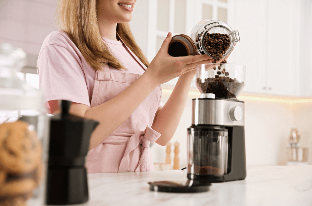 Woman pouring coffee beans in electric coffee  grinder