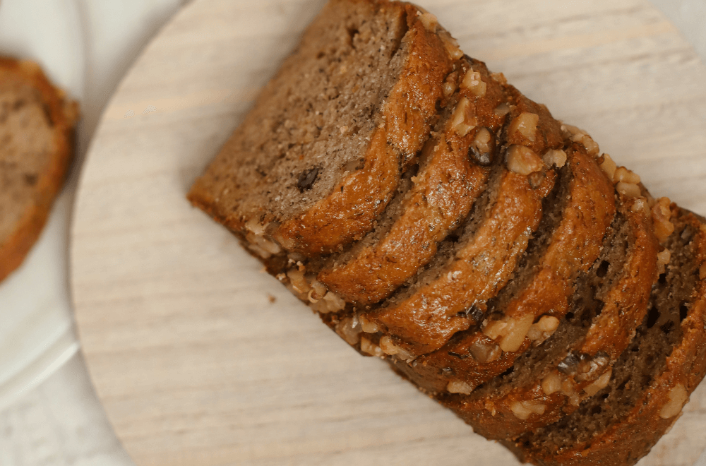 Banana Walnut & Pecan Loaf sliced in rounded wooden table