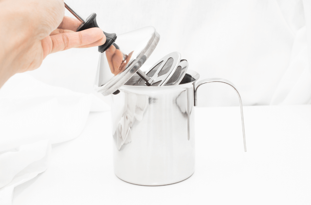 Manual milk frother Coffee and foam drink-making equipment on table white background.