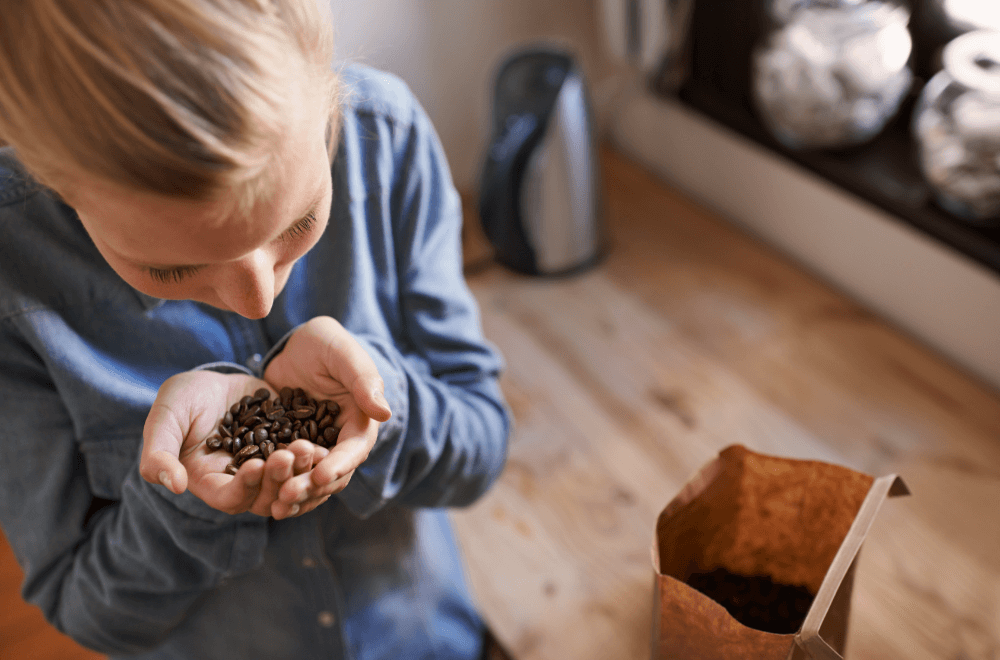 A young woman smelling fresh coffee beans in her kitchen