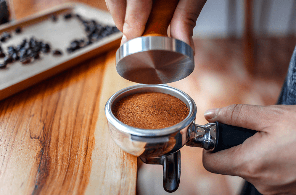Close-up of hand Barista cafe making coffee with manual presses ground coffee using tamper
