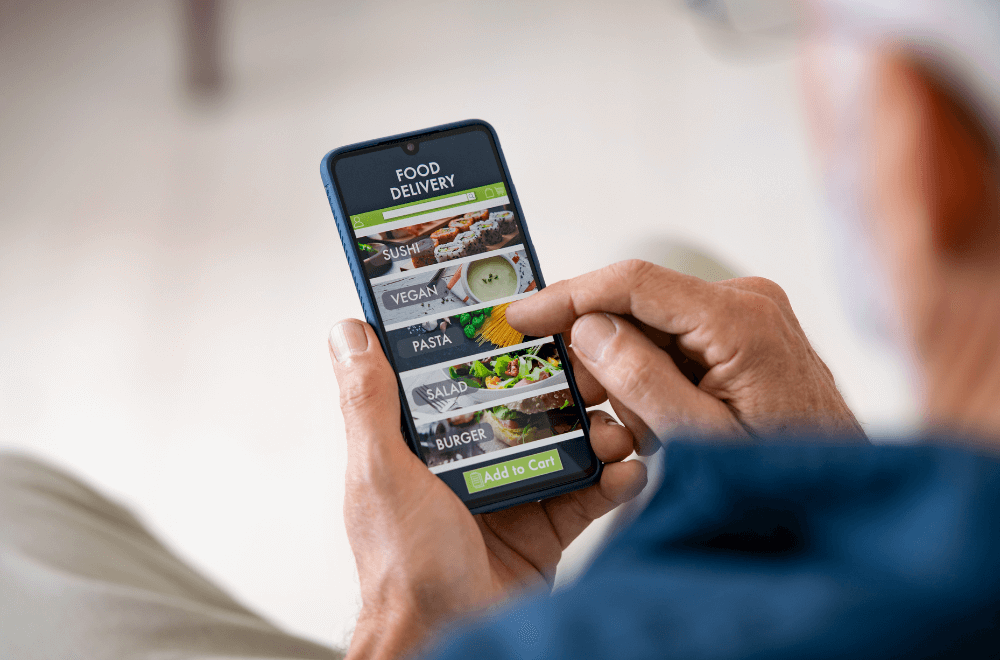 A man hands hold smartphone ordering food to be delivered at home
